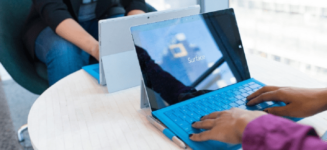 Two people at a desk typing on laptops